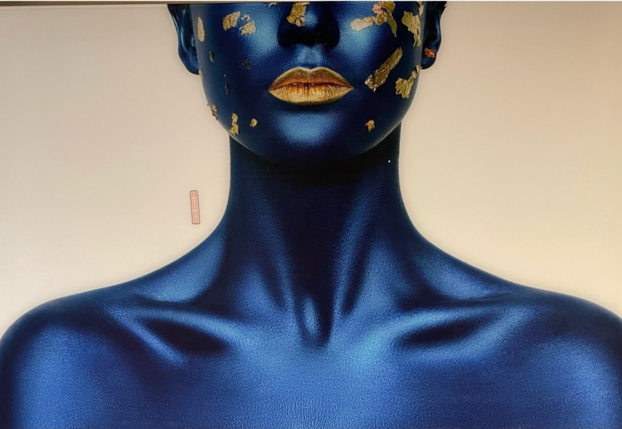 Torso painted metallic blue, gold flecks on face, gold lips.