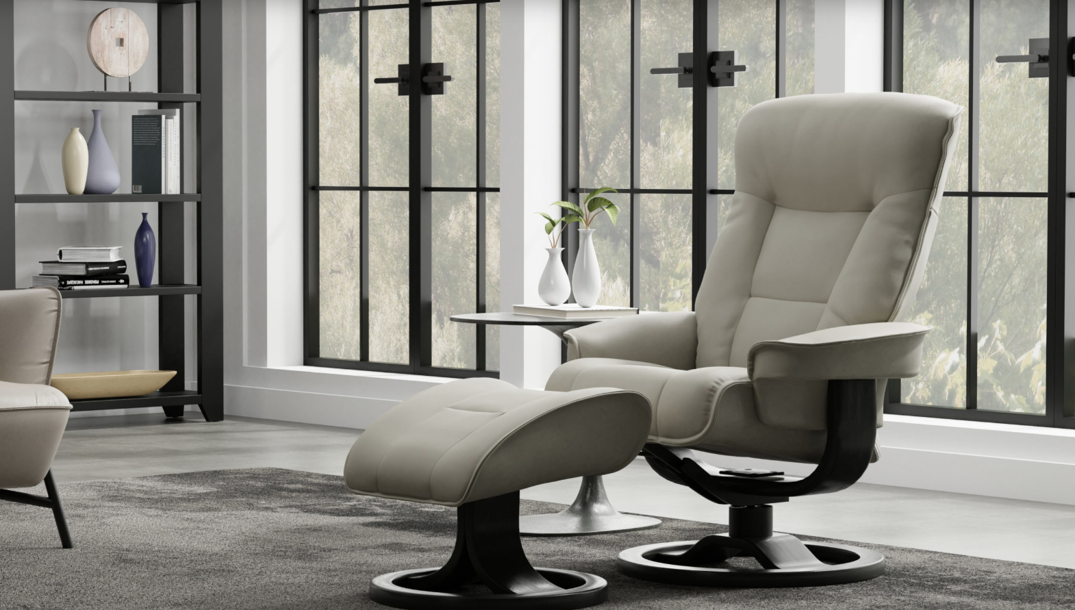 A light beige reclining chair and matching ottoman with black bases, positioned in a room with large windows and shelving.