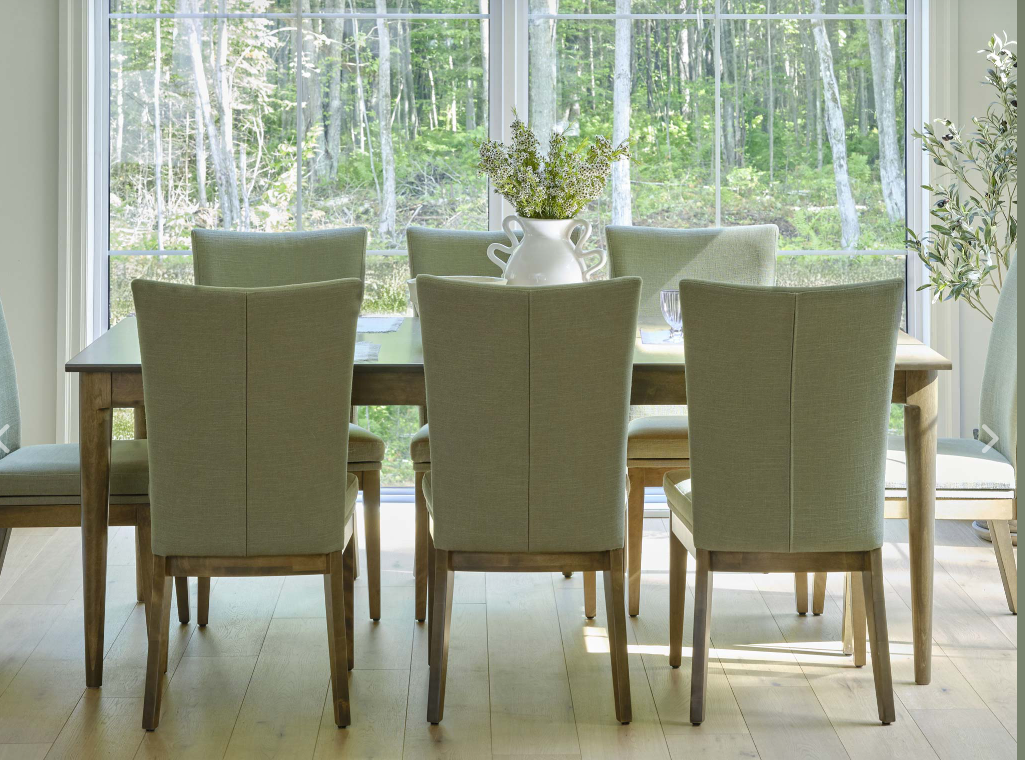 Dining room with a dark wood table, black chairs with fur throws, and a brick fireplace.