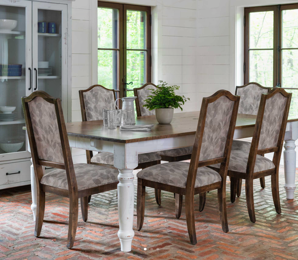 Dining room with a white table and chairs, set for a meal, against a window with an outdoor view.