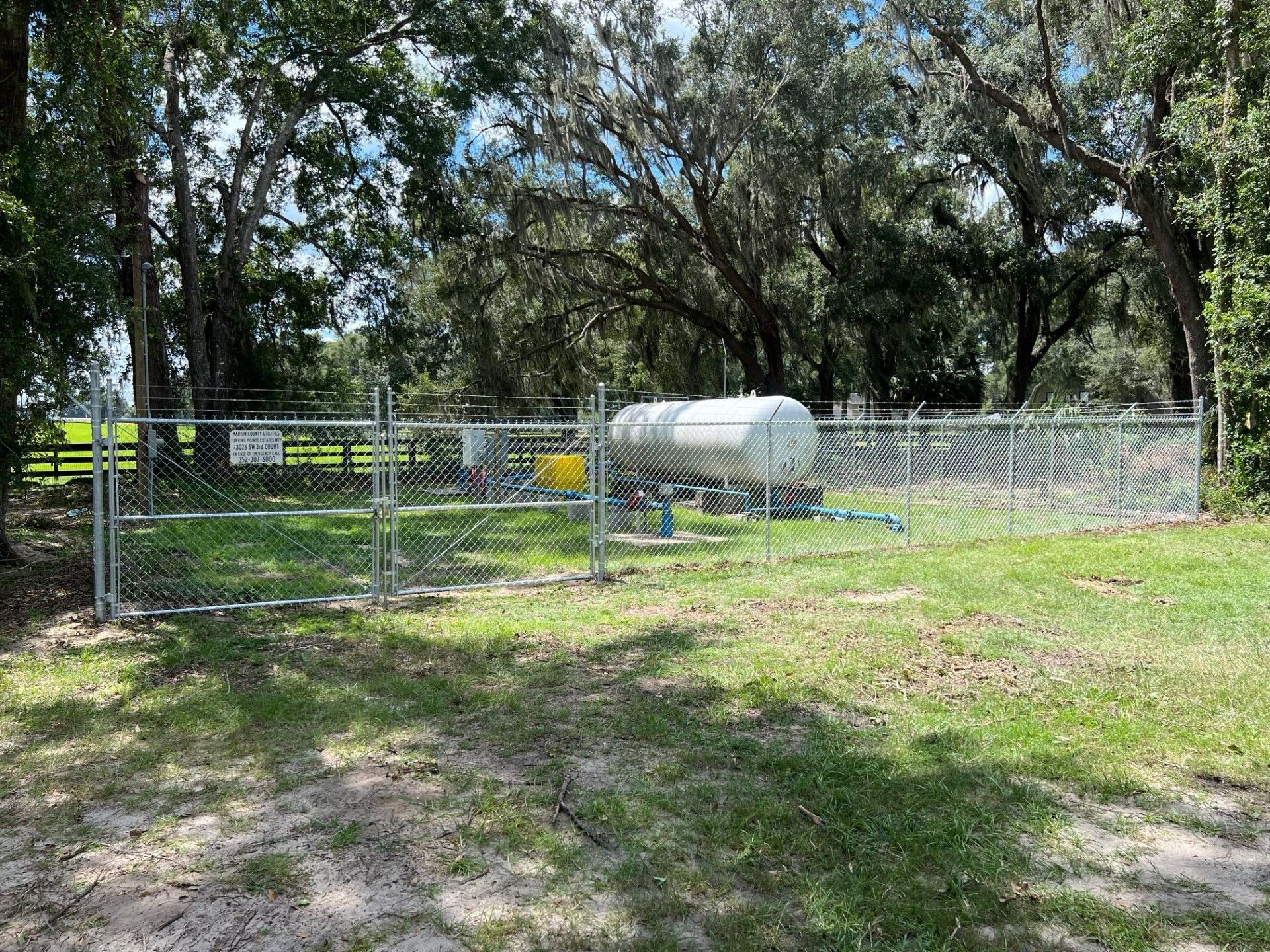 Commercial fence installation around a large tank with barbed wire on top