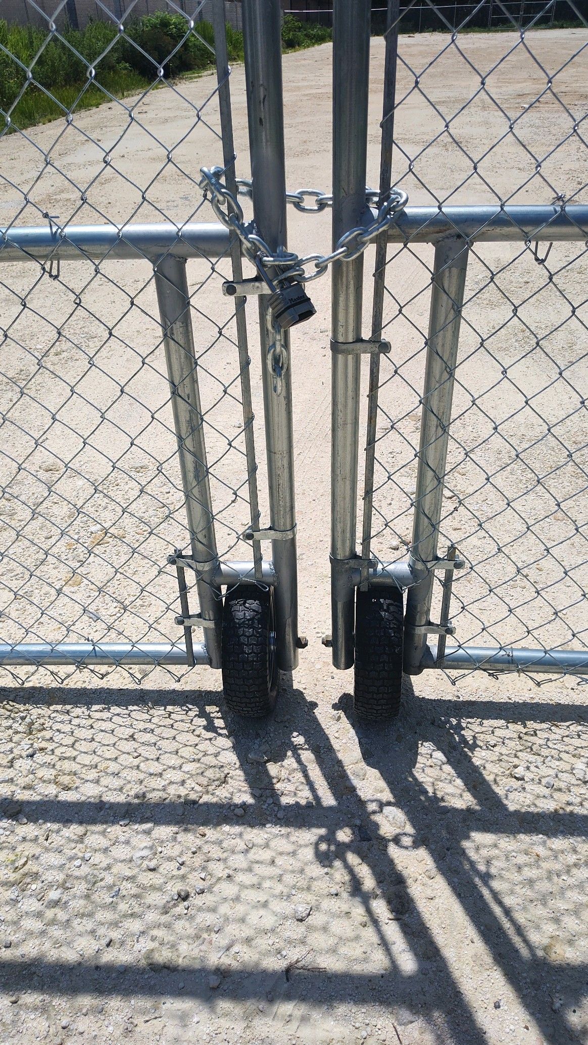Industrial chain link fence with wheels and a chain with a padlock.