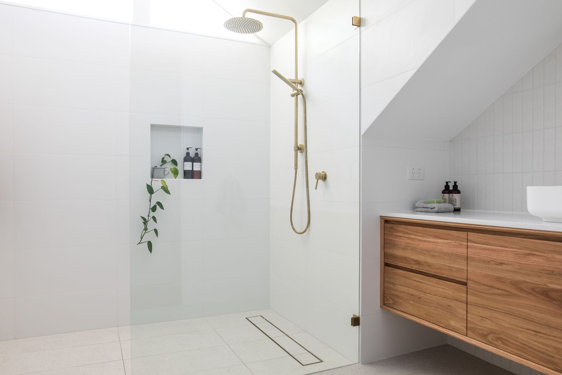 Modernes weißes Badezimmer mit goldenen Duscharmaturen, Glaswand und Waschtisch aus Holz
