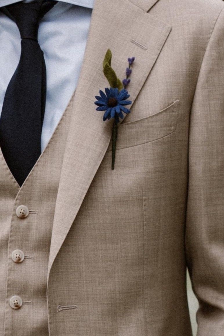 Bruidegom met een corsage van bloemen gemaakt van vilt, blauwe spaanse margriet, lavendel en een klein blad
