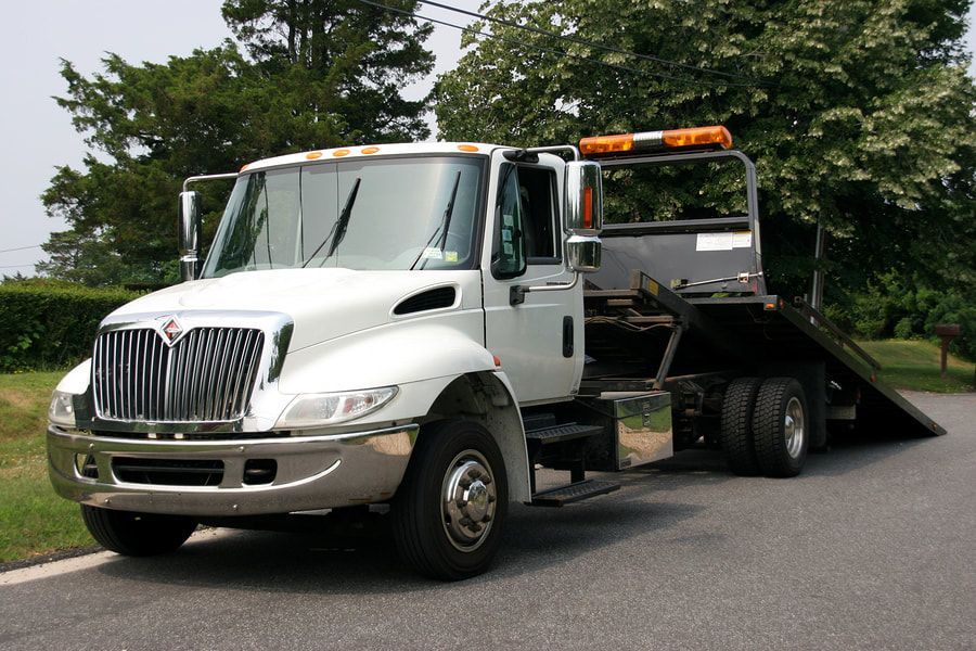 A white tow truck is parked on the side of the road.