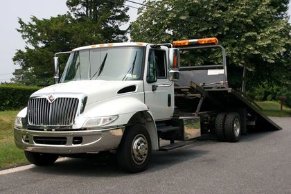 A white tow truck is parked on the side of the road.