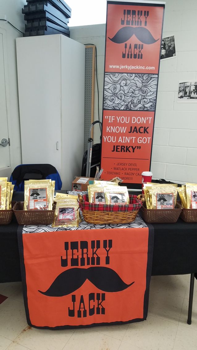 A man in a bigfoot costume is standing in front of a table that says jerky