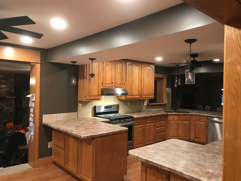 Modern kitchen with wood cabinets, granite counters, gas stove, and stainless steel dishwasher under recessed lights