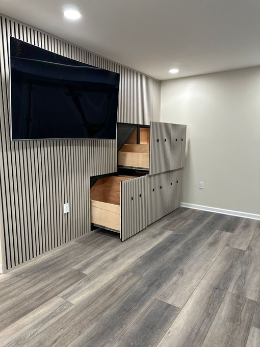 Empty room with gray wood floor, striped accent wall, and a small wooden cat bed by the window.