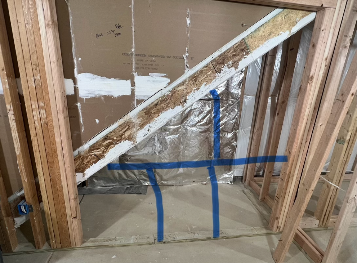 Framed wall with diagonal brace and ductwork covered in reflective insulation, taped with blue tape
