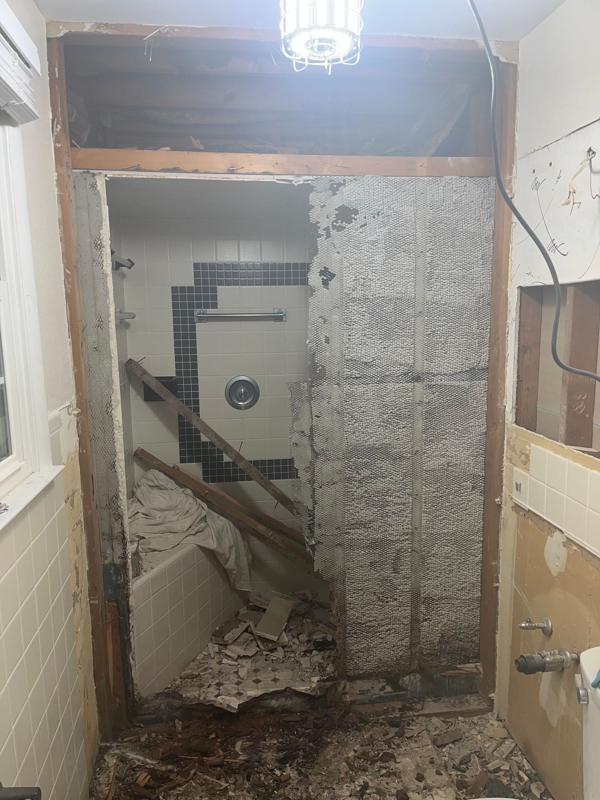 Damaged hallway with exposed walls, debris, and a broken doorway leading into another room.