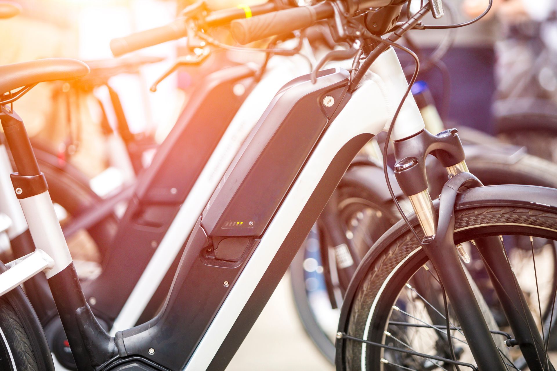Close-up of parked electric bicycles in warm sunlight, with black frames and front wheels visible