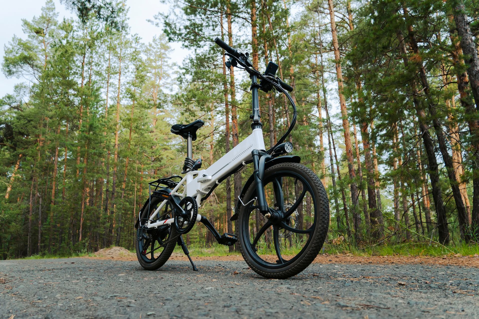 White mountain bike on a gravel path in a forest with tall green trees