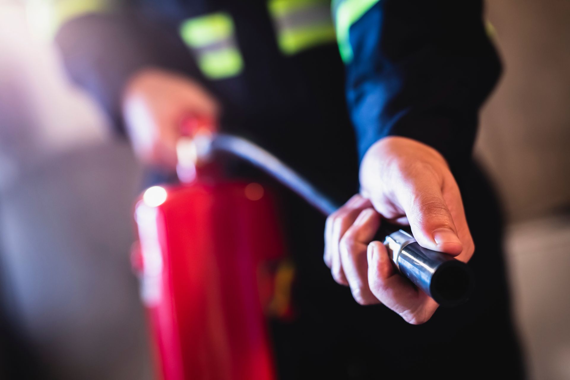 A cropped view of a man in uniform using a fire extinguisher.