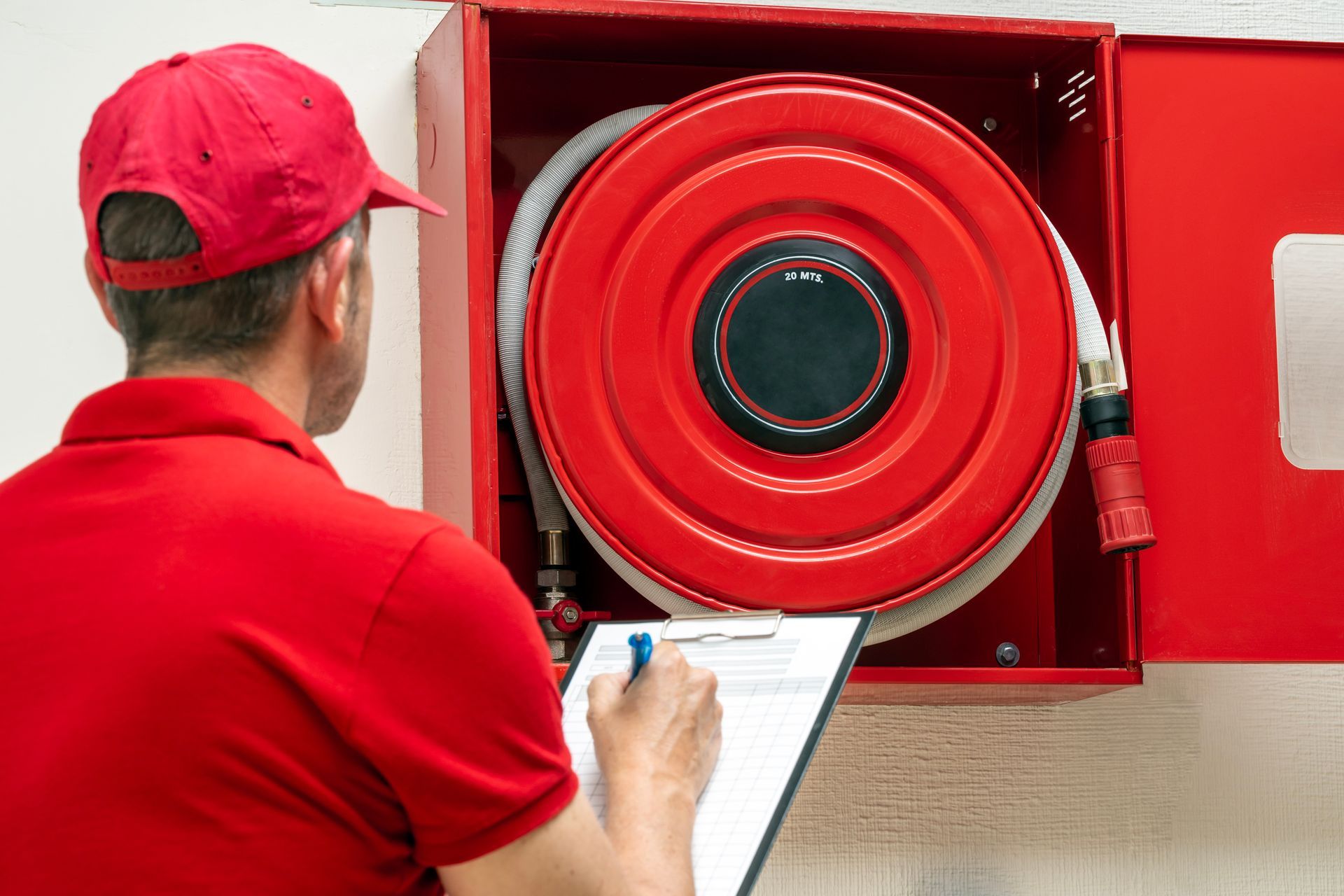 A fire safety technician performing an inspection of a fire hose cabinet. A fire safety technician performing an inspection of a fire hose cabinet.