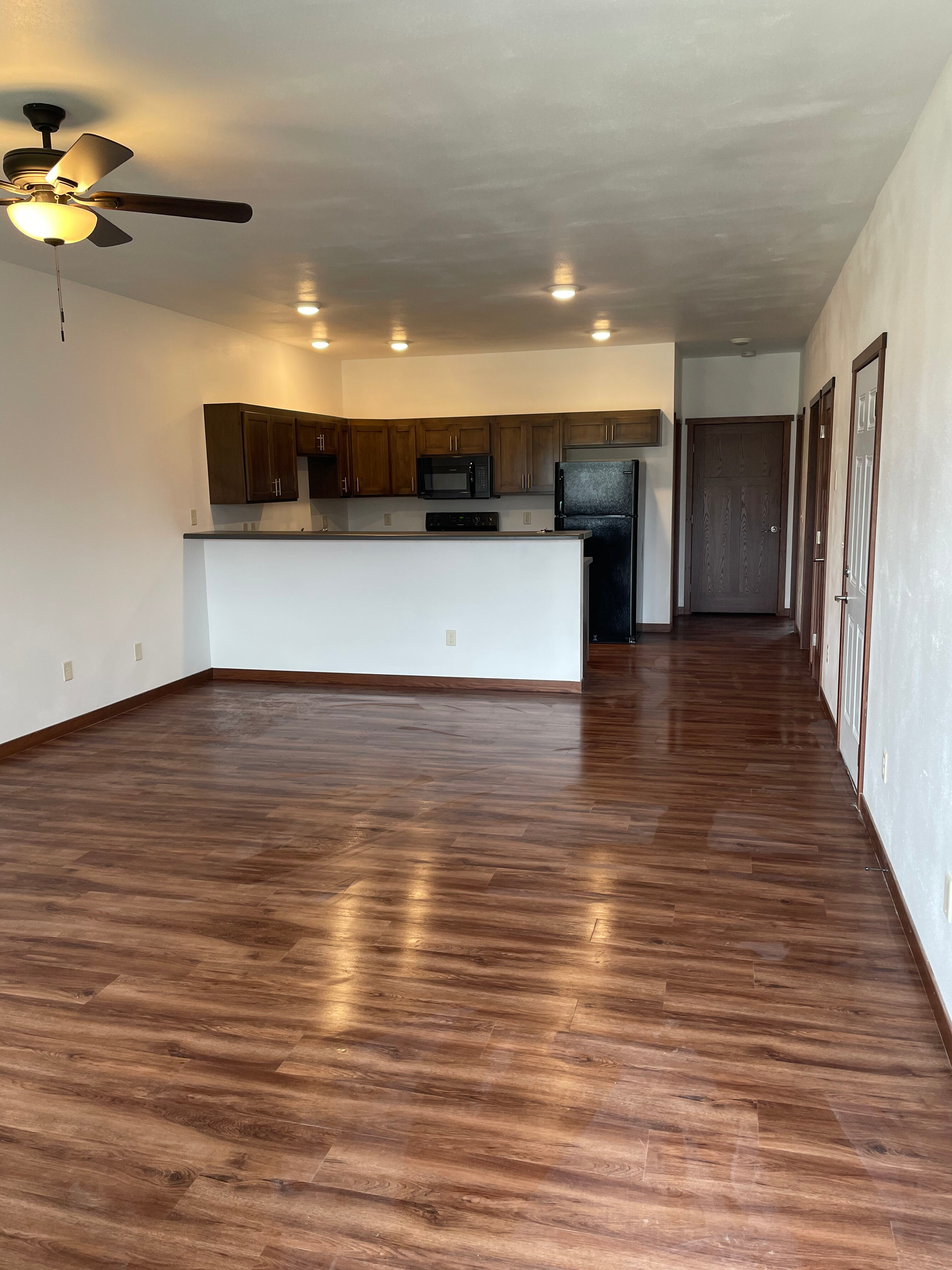 An empty living room with hardwood floors and a ceiling fan.