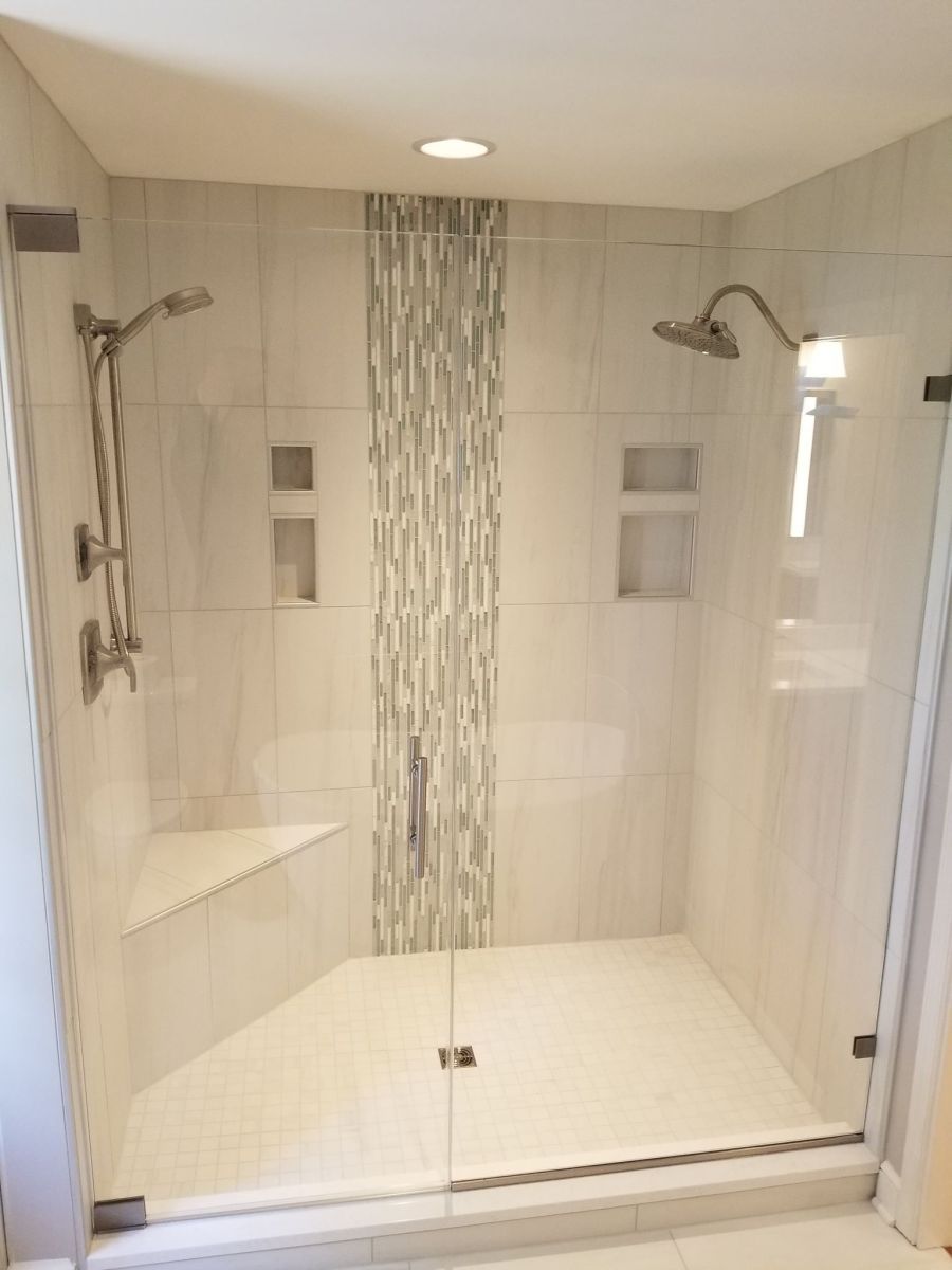 A bathroom with a walk in shower with a glass door.
