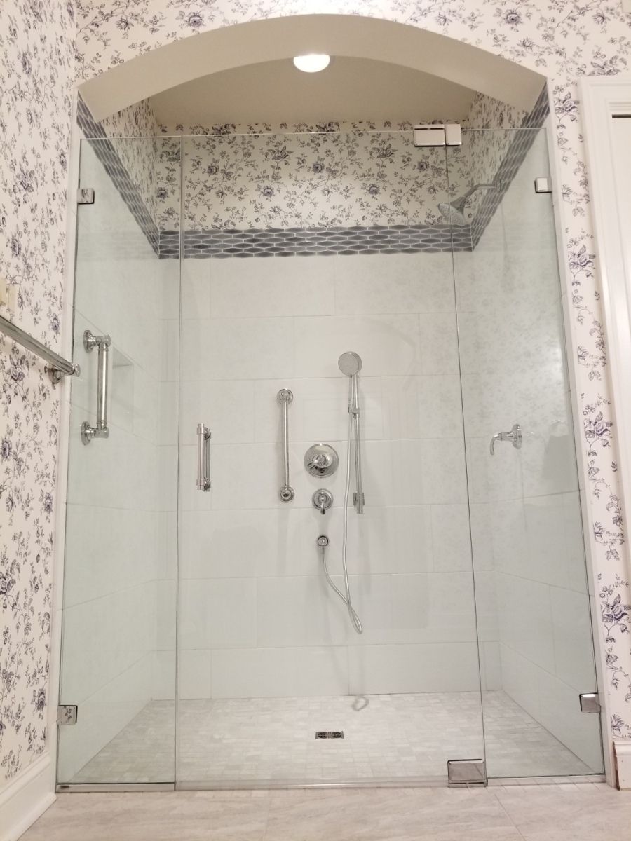 A bathroom with a walk in shower with a glass door