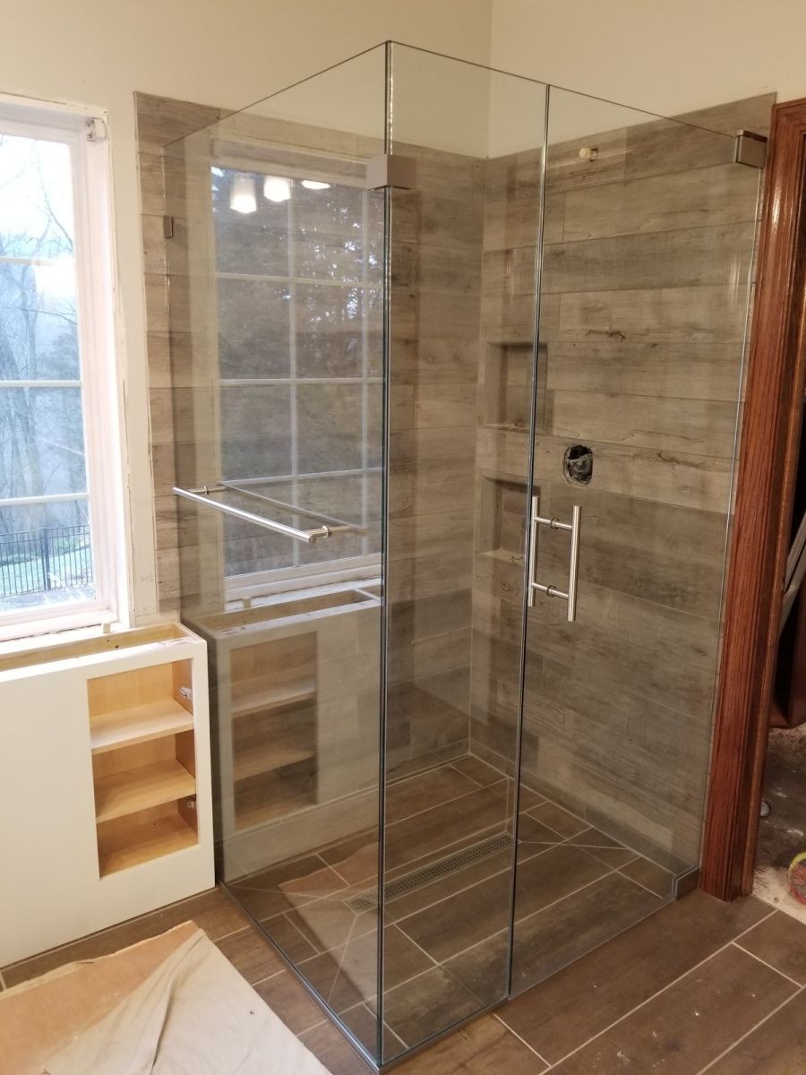 A bathroom with a walk in shower with a glass door.