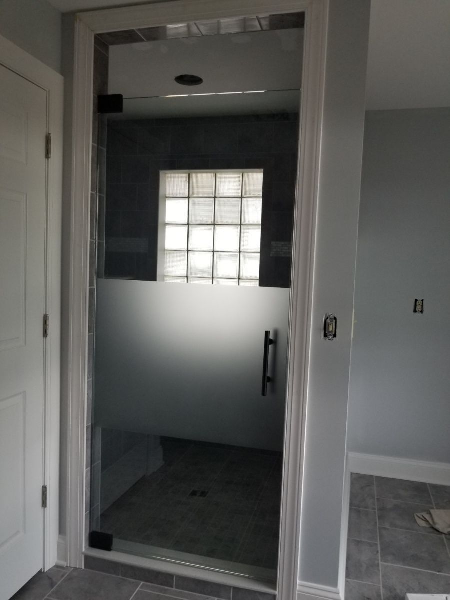 A bathroom with a glass shower door and a window