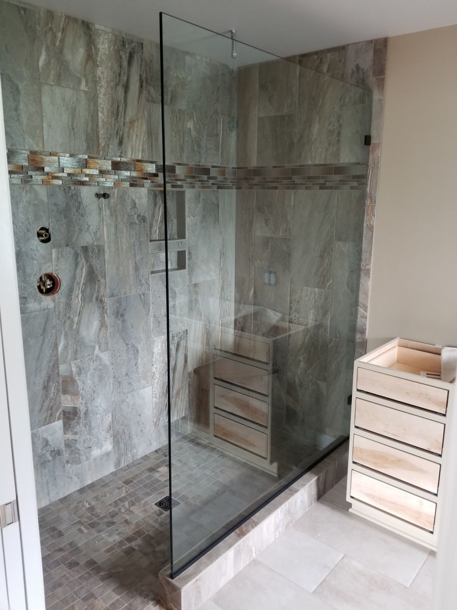 A bathroom with a walk in shower with a glass door.
