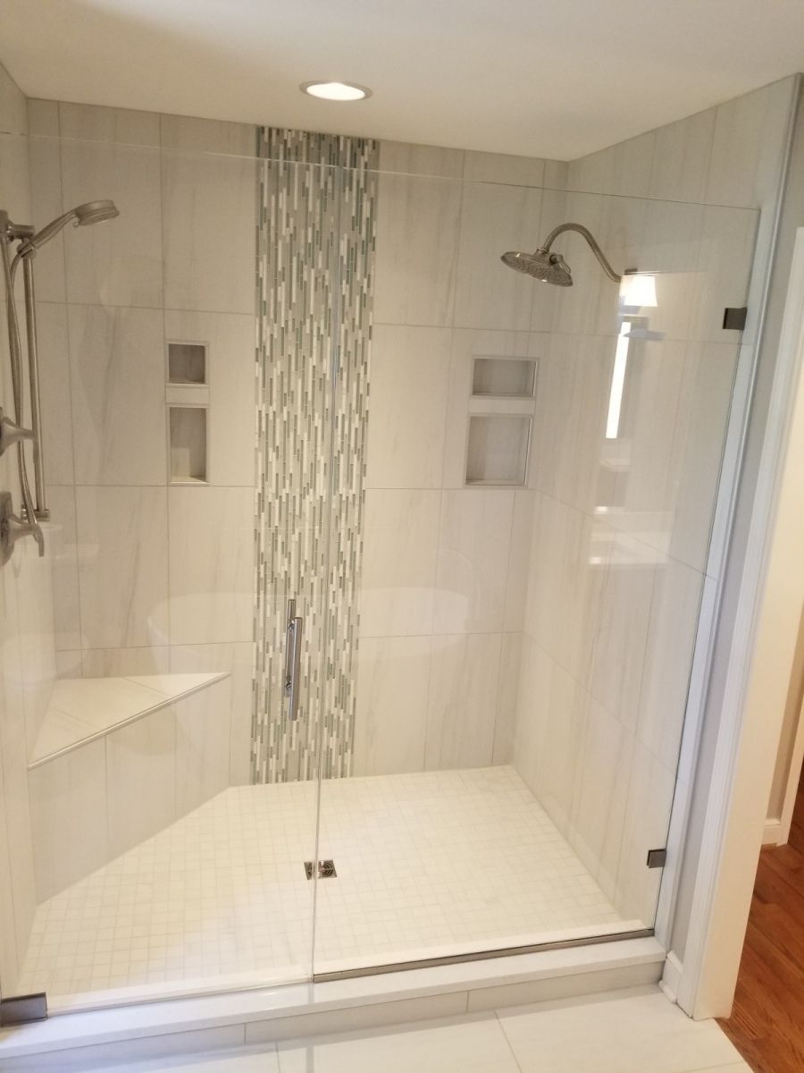 A bathroom with a walk in shower with a glass door.