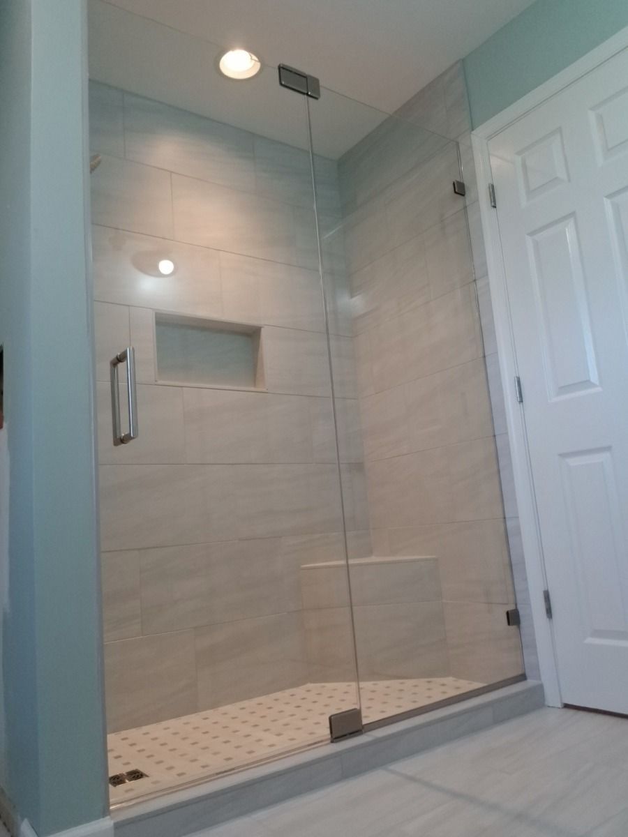 A bathroom with a walk in shower with a glass door.