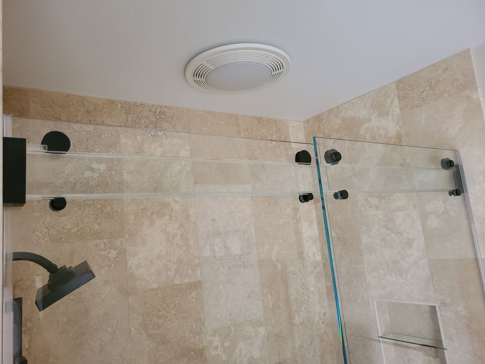A bathroom with a shower head and a ceiling fan.