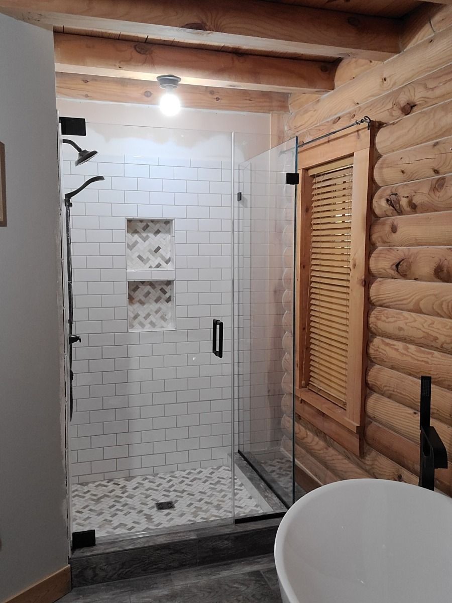 A bathroom in a log cabin with a walk in shower and a tub.