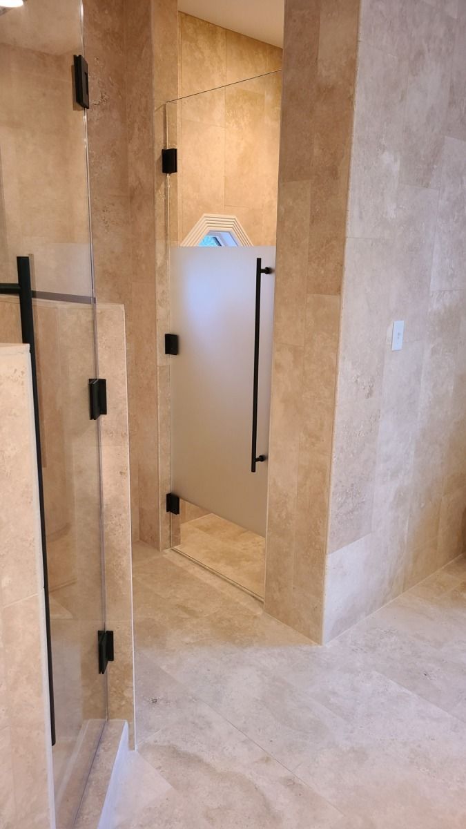 A bathroom with a walk in shower and a glass door.