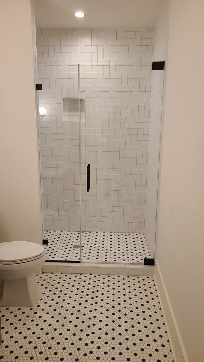 A bathroom with a toilet and a walk in shower with a glass door.