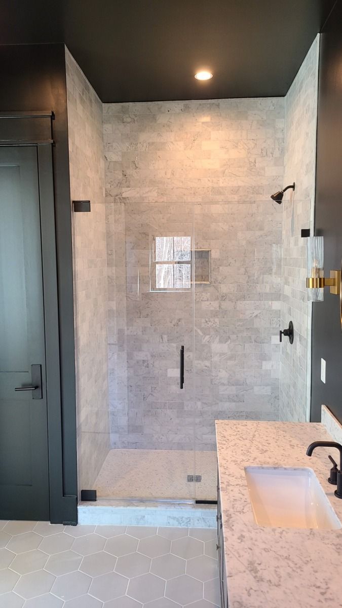 A bathroom with a walk in shower and a sink.