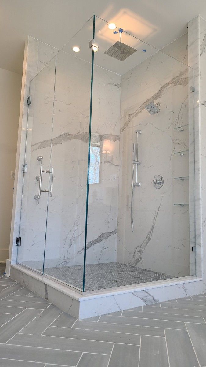 A bathroom with a walk in shower with a glass door.