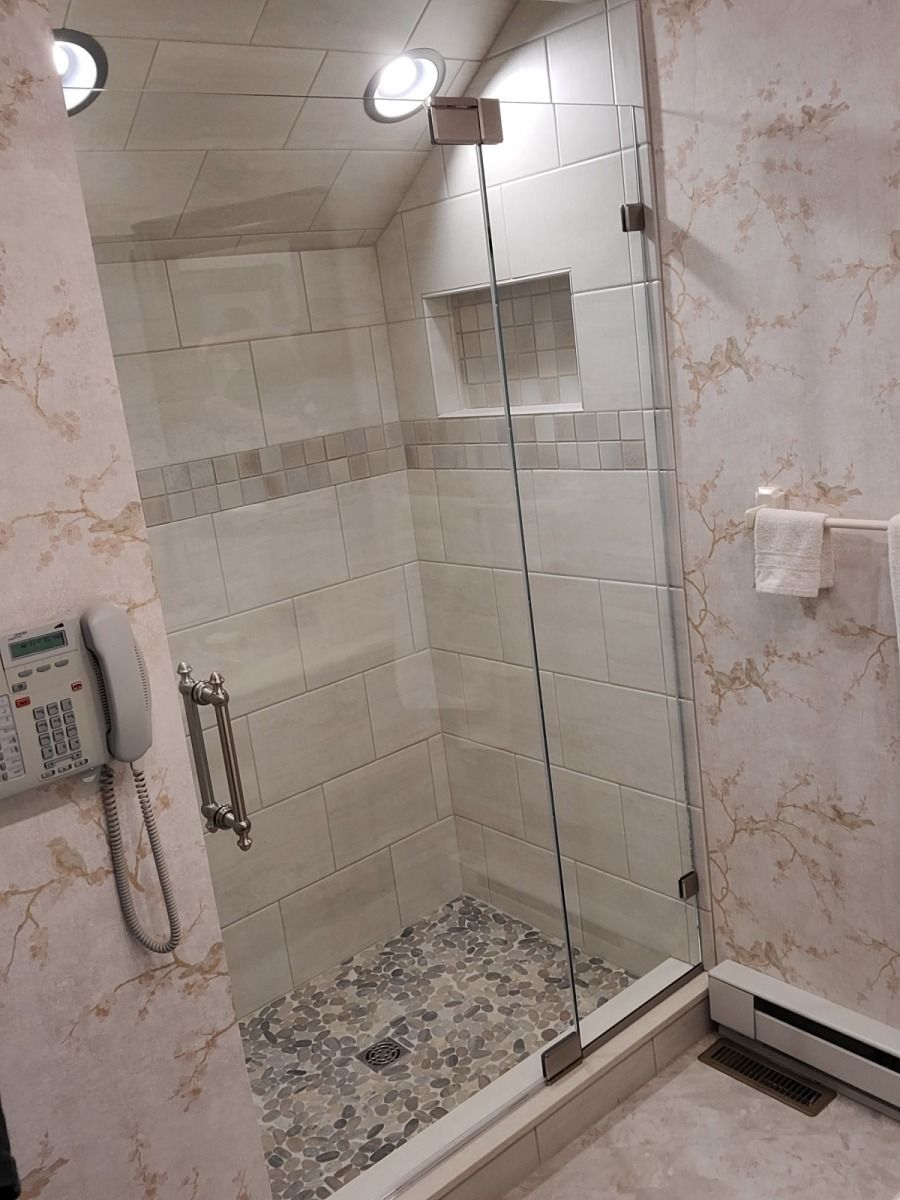 A bathroom with a walk in shower and a phone on the wall.