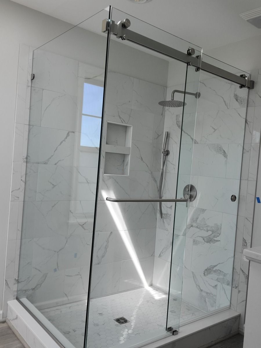 A shower stall with sliding glass doors in a bathroom.