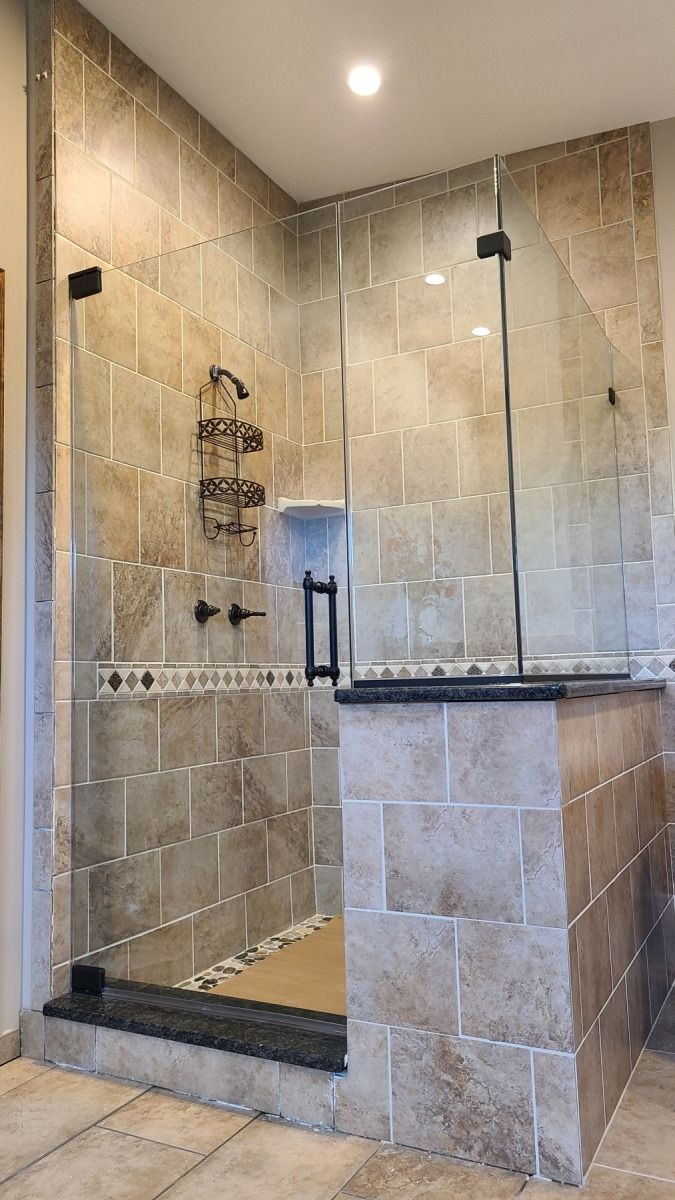 A bathroom with a walk in shower with a glass door.