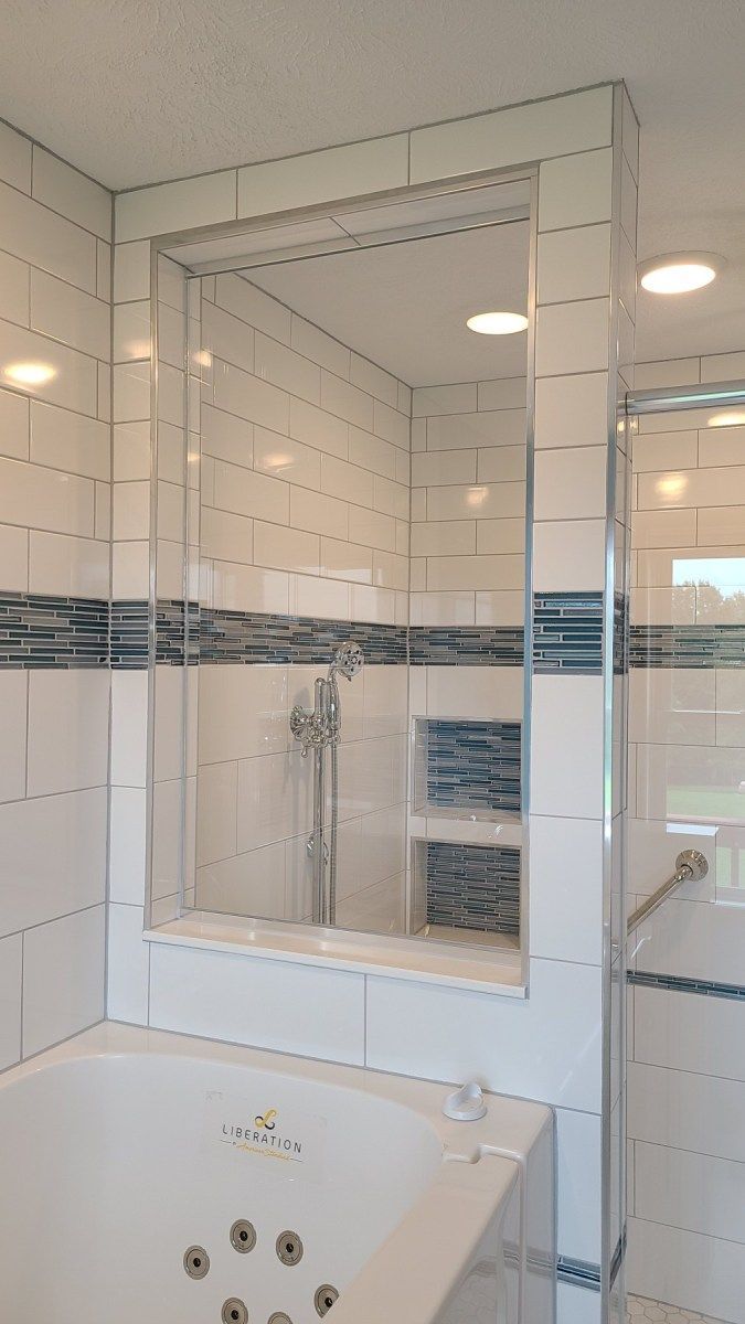 A bathroom with a tub , shower , and mirror.