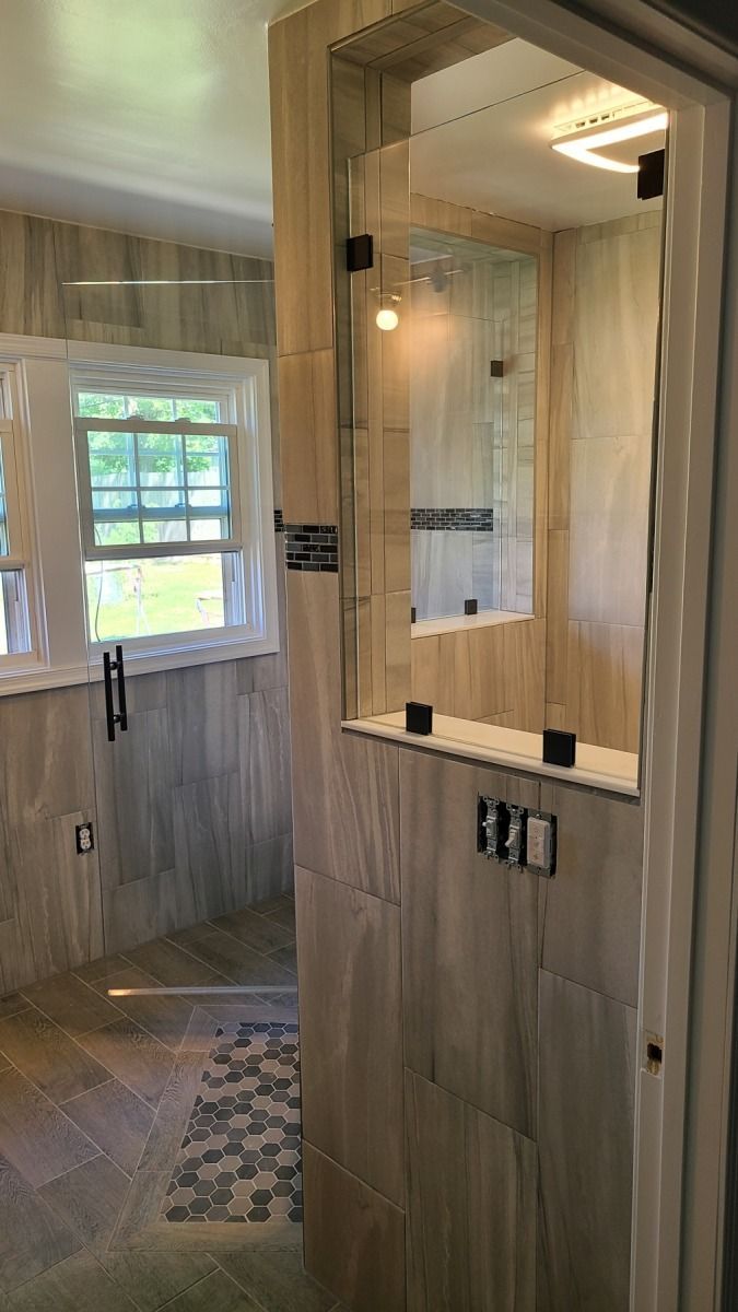 A bathroom with a walk in shower and a window.