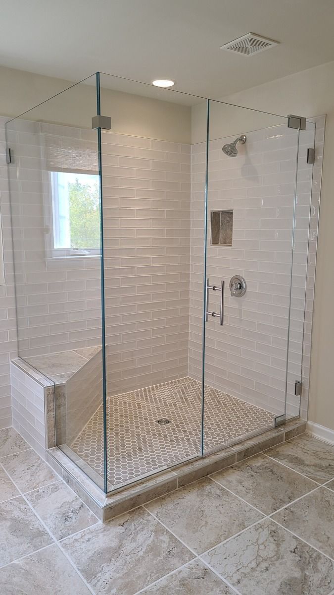 A bathroom with a walk in shower with a glass door.