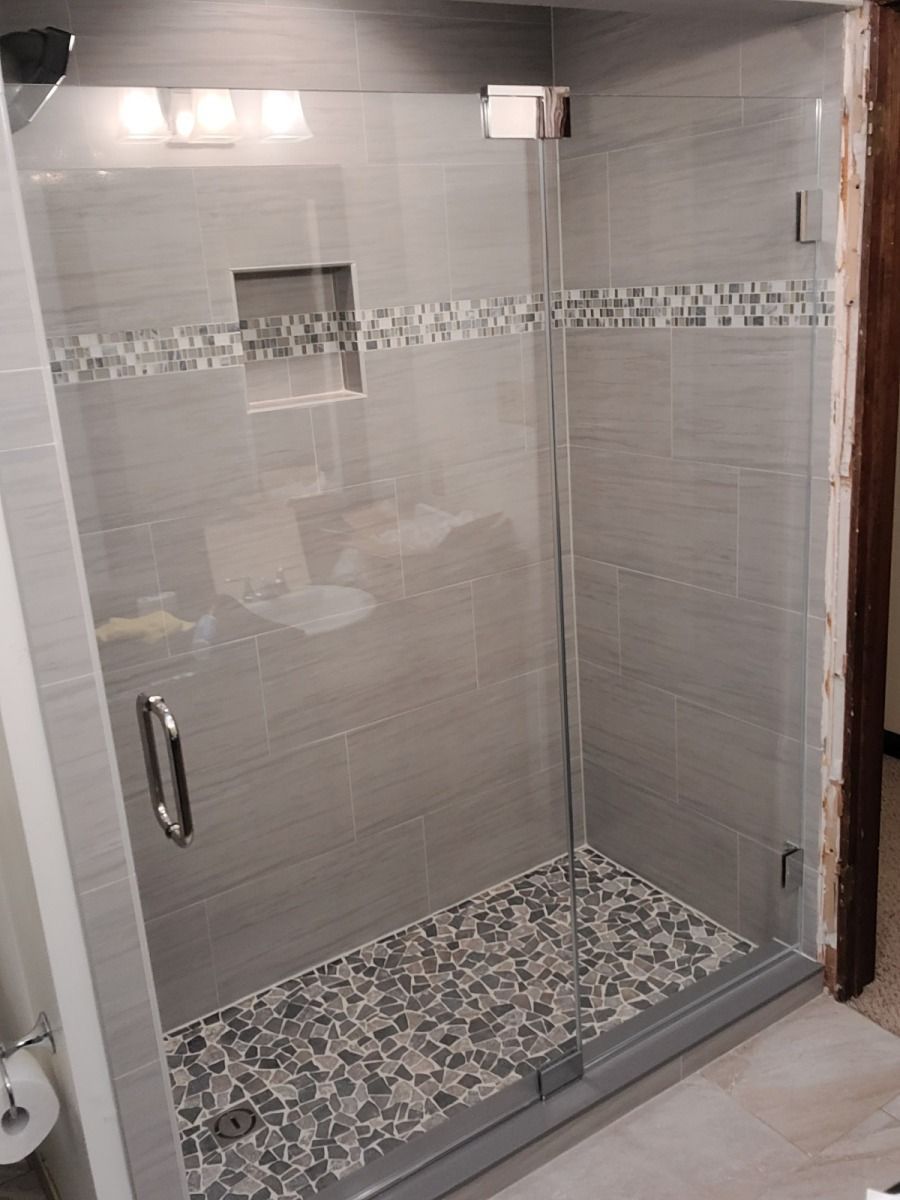 A bathroom with a walk in shower with a glass door.