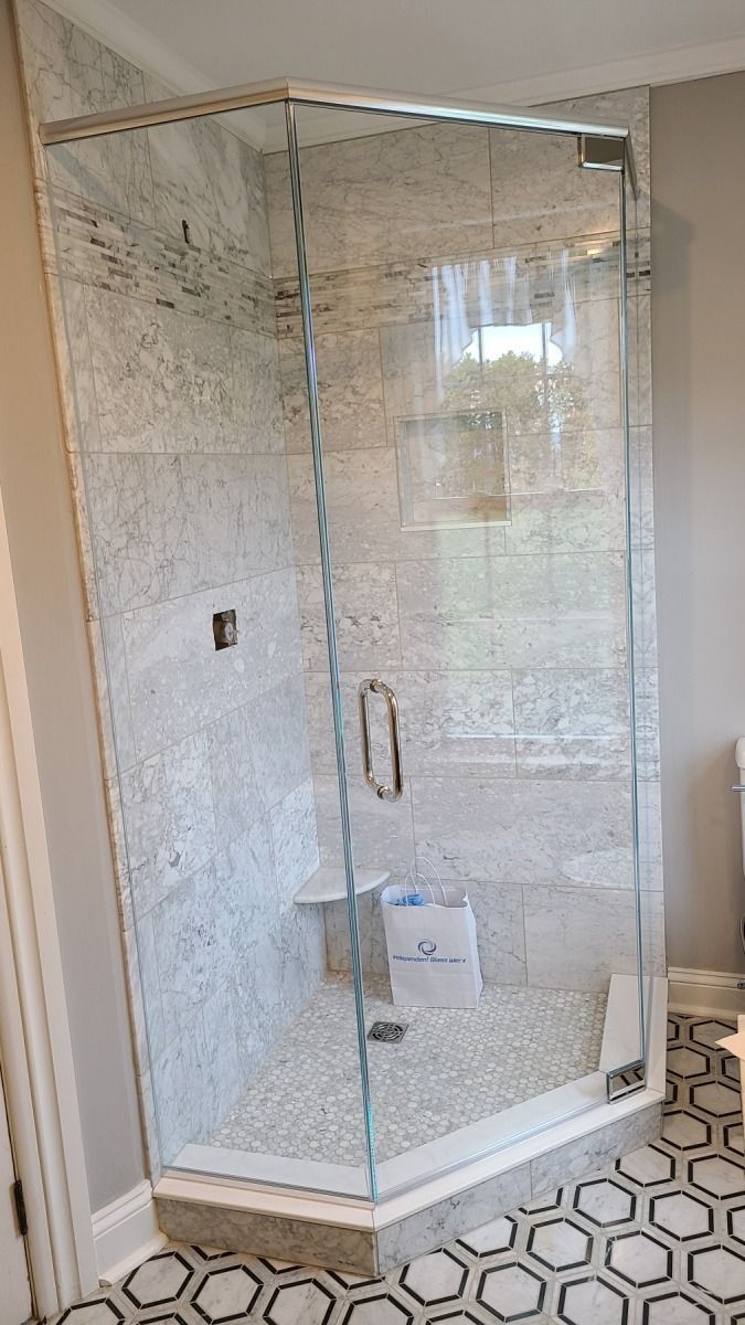 A bathroom with a glass shower door and a tiled floor.