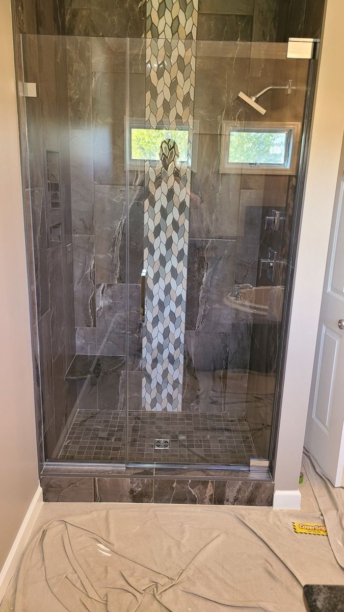 A bathroom with a walk in shower with a glass door.