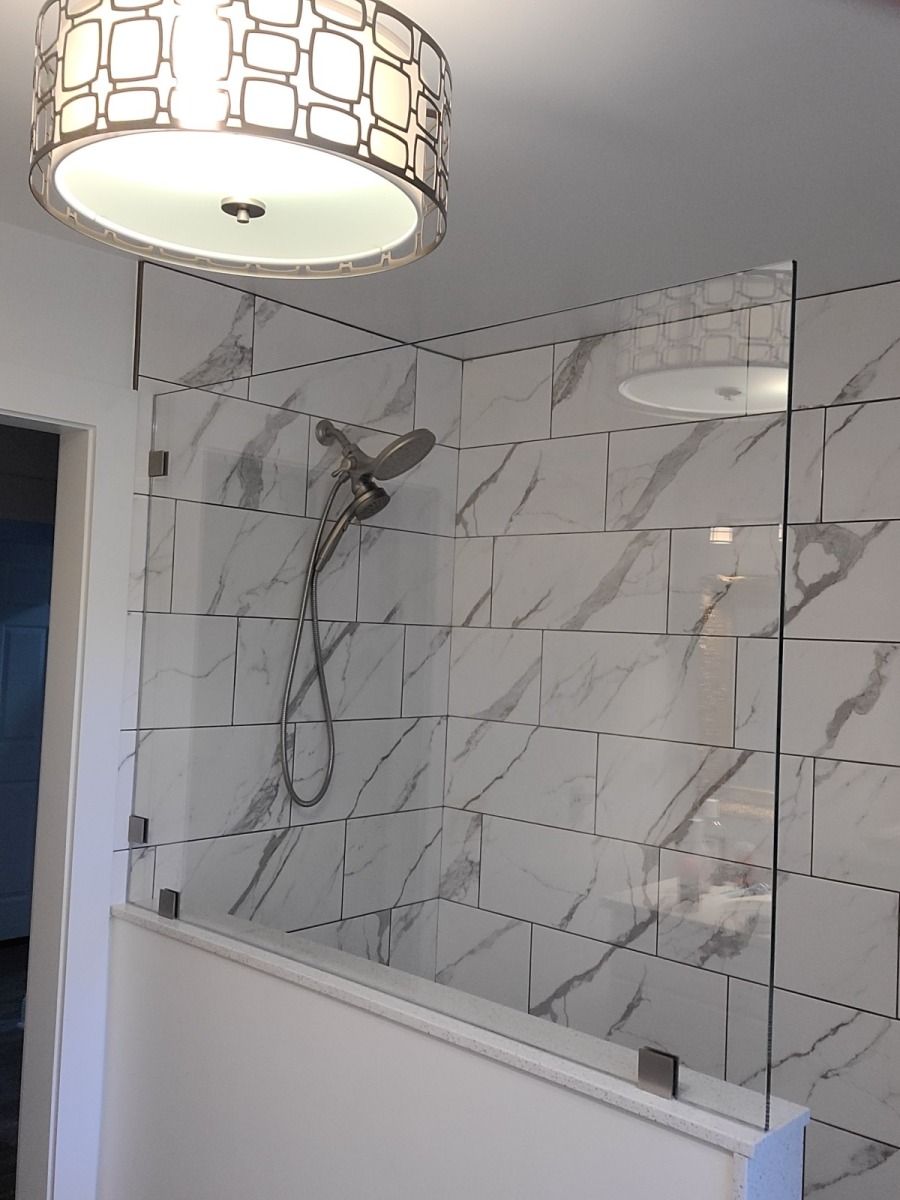 A shower with a glass door and a light hanging from the ceiling