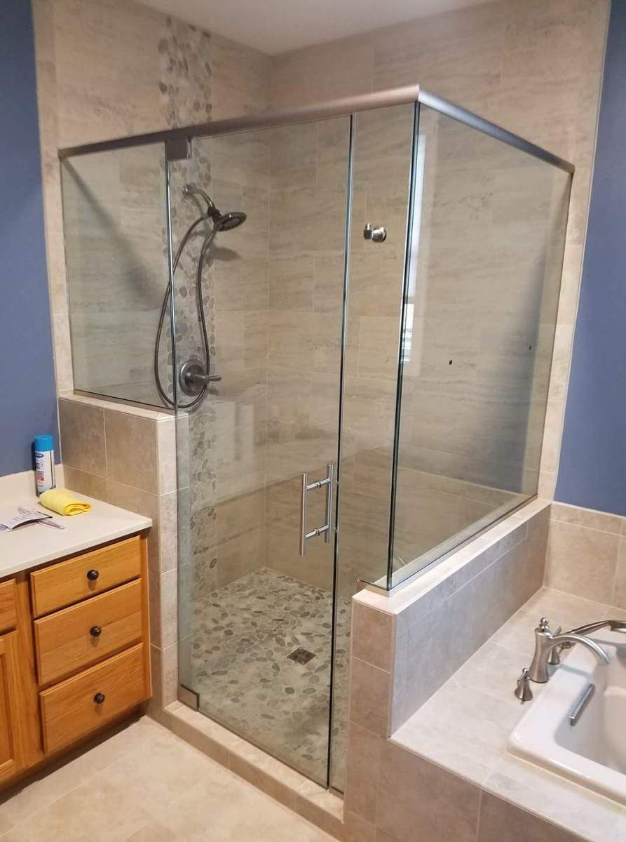 A bathroom with a glass shower door and a bathtub.