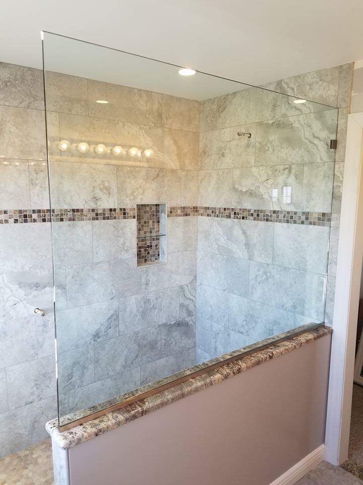 A bathroom with a walk in shower with a glass door.