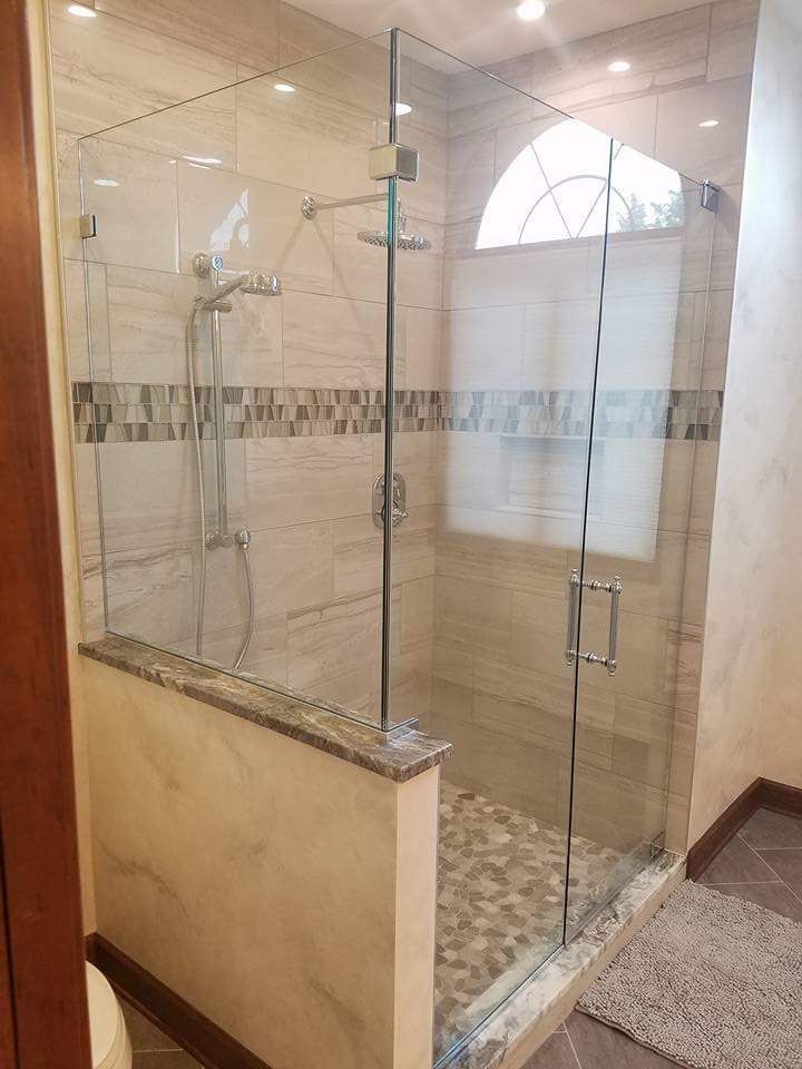 A bathroom with a walk in shower with a glass door.