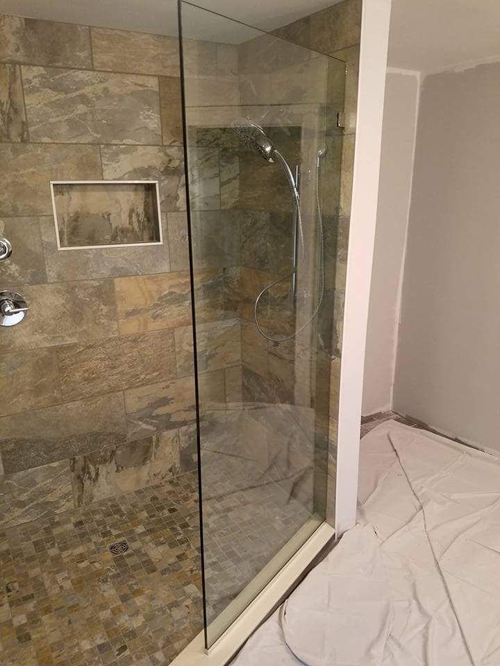A bathroom with a walk in shower with a glass door.