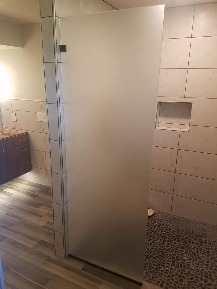 A bathroom with a walk in shower and a glass door.