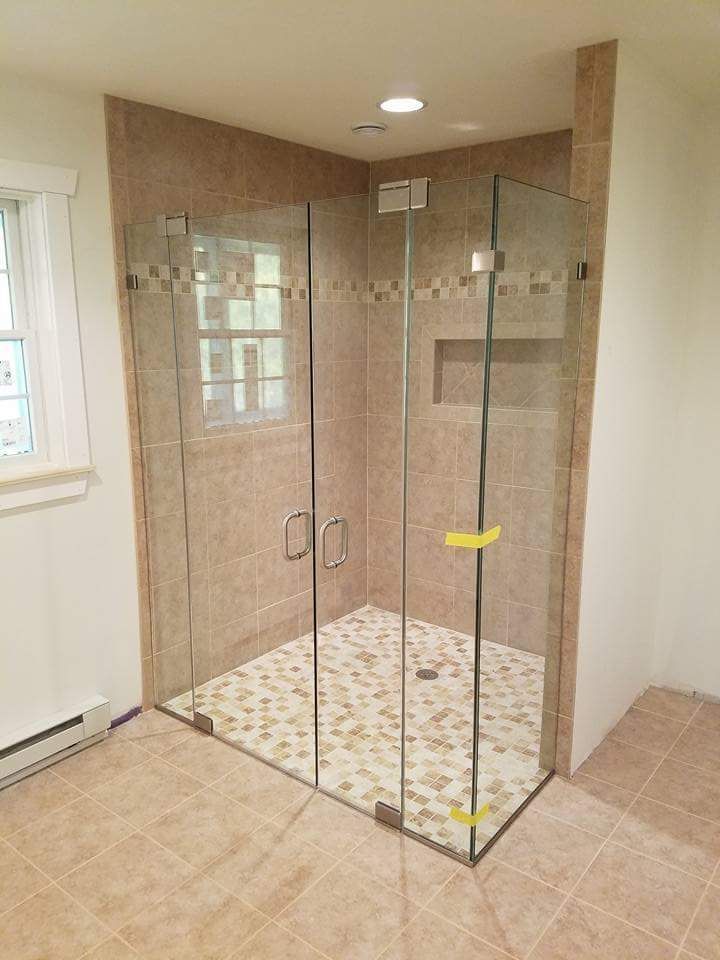 A bathroom with a walk in shower with a glass door.