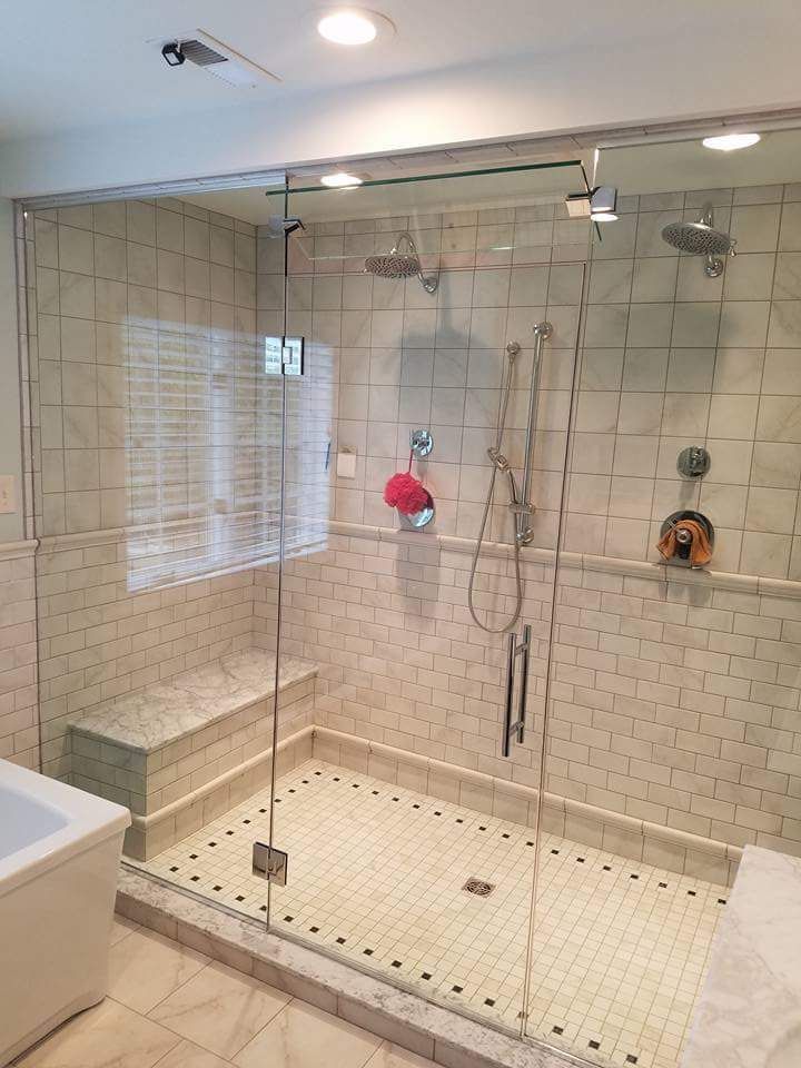 A bathroom with a walk in shower with a glass door.